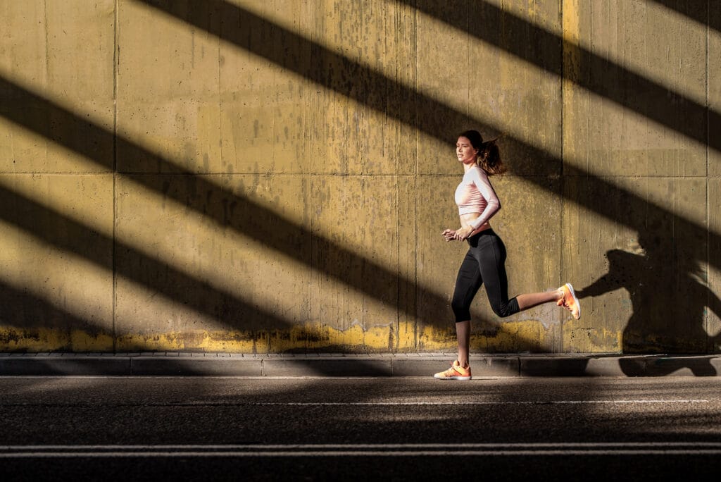 A woman running outside, which is a natural way to improve mental health.