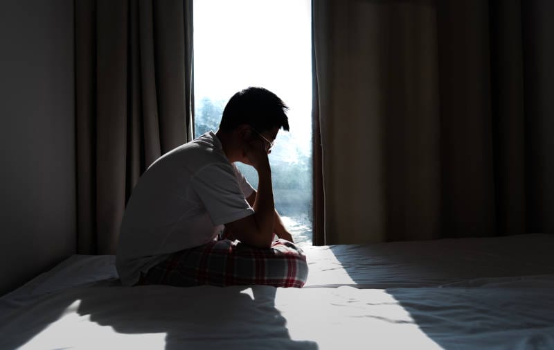 A man experiencing depression in a dark room.